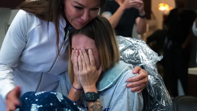 Still from the film: a dentist hugs a patient, who covers her face with her hands.
