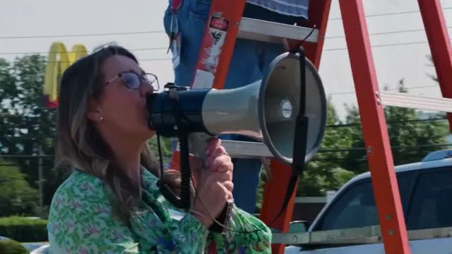 A woman speaks through a megaphone outdoors.