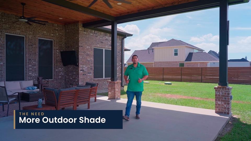 A man in a green polo walks across a covered patio beside a brick home. On-screen label: “The need: More Outdoor Shade.”